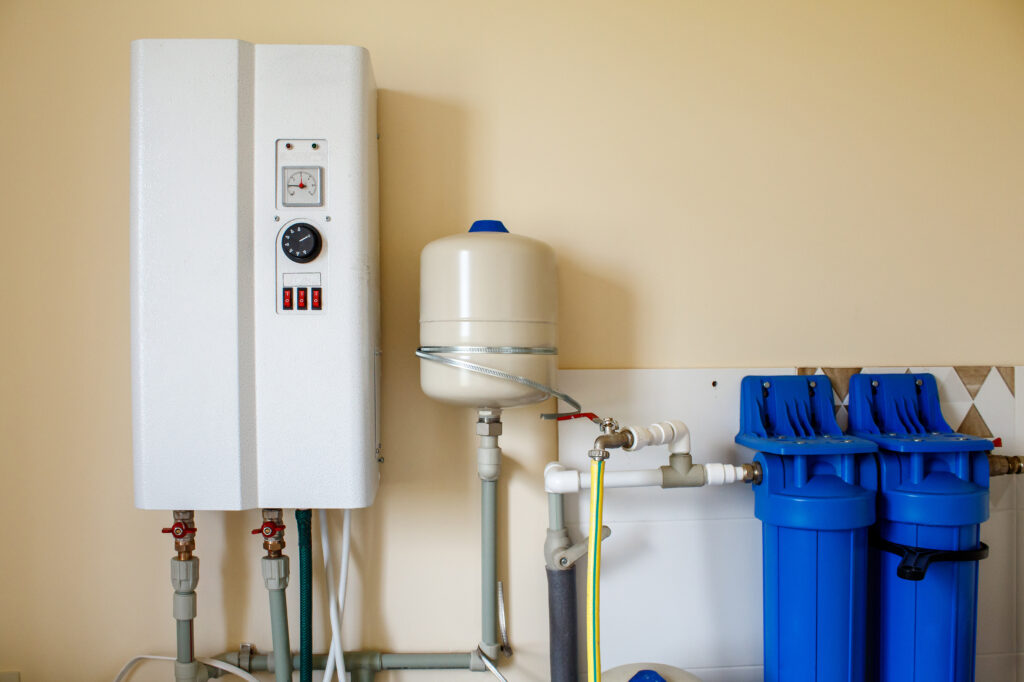 Tankless water heater mounted on the wall with gas tank and pipes next to it