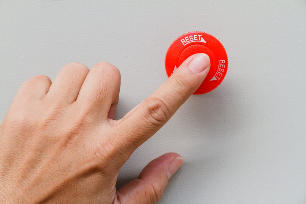 Person's finger on red reset button