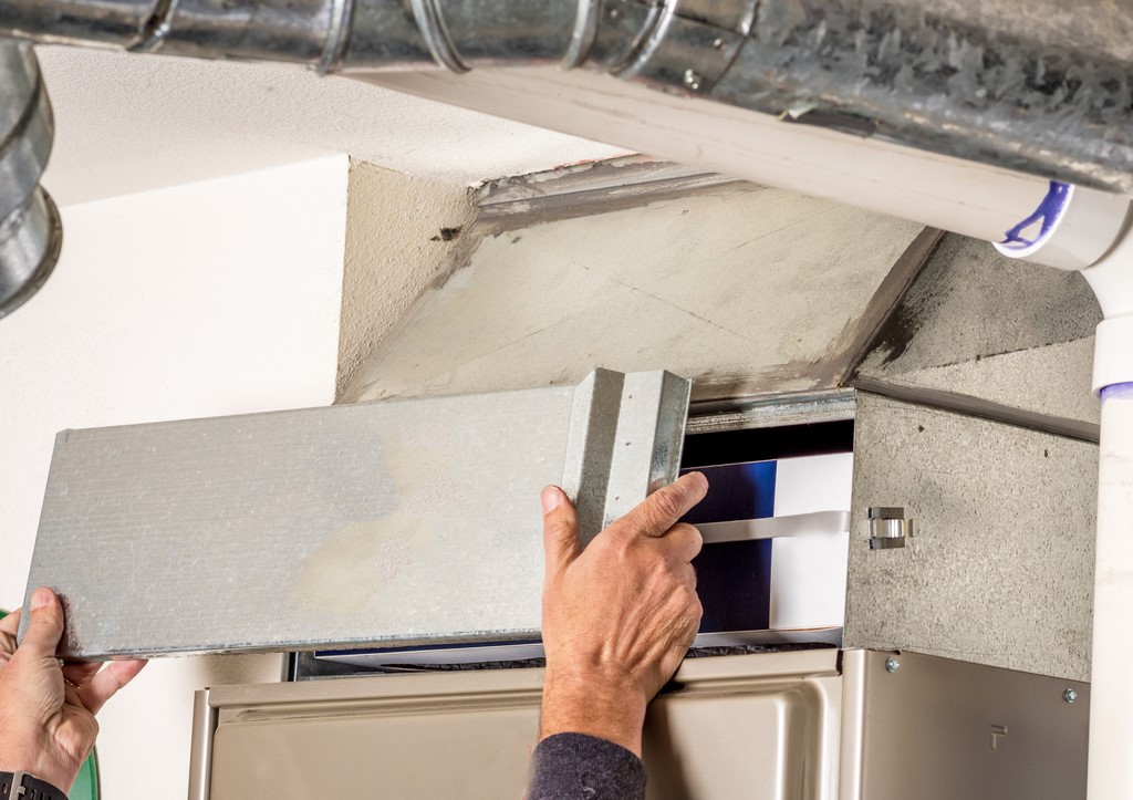 HVAC technician replacing the access door of a furnace in Chesterland, OH